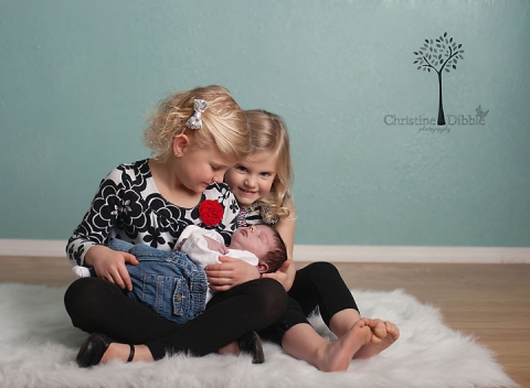 big sisters holding new baby