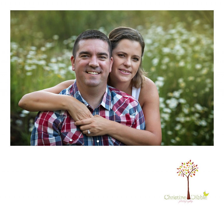 An engeged couple sit among a field of wildflowers while Sonora, CA engagement and wedding photographer Christine Dibble Photography takes their photos.