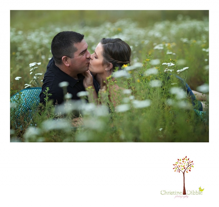 An engeged couple sit on a quilt among a field of wildflowers while Sonora, CA engagement and wedding photographer Christine Dibble Photography takes their photos.