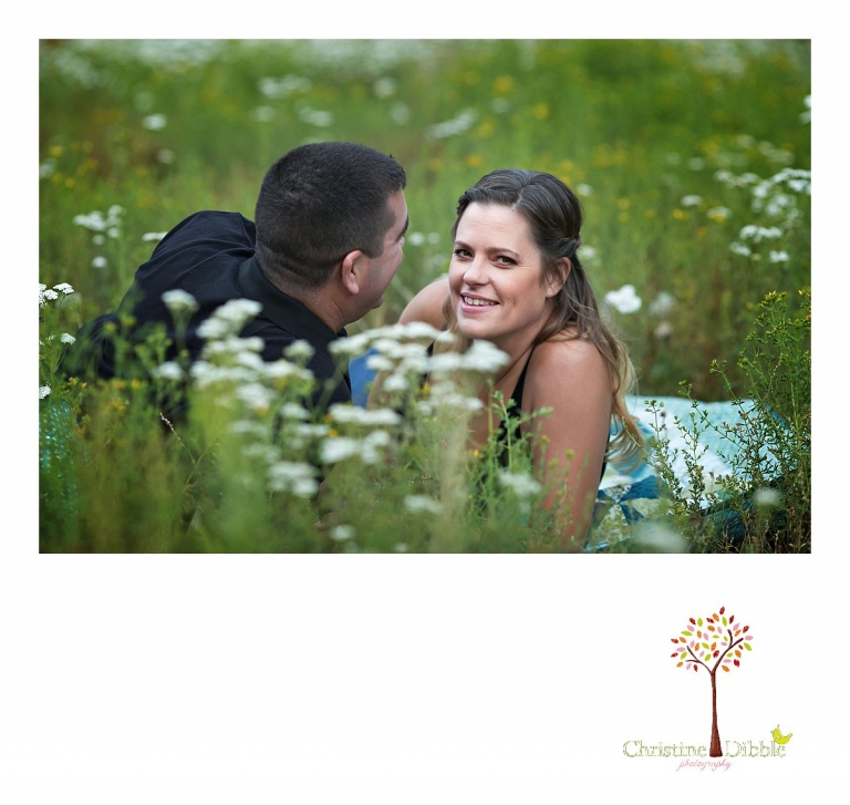 An engeged couple sit on a quilt among a field of wildflowers while Sonora, CA engagement and wedding photographer Christine Dibble Photography takes their photos.