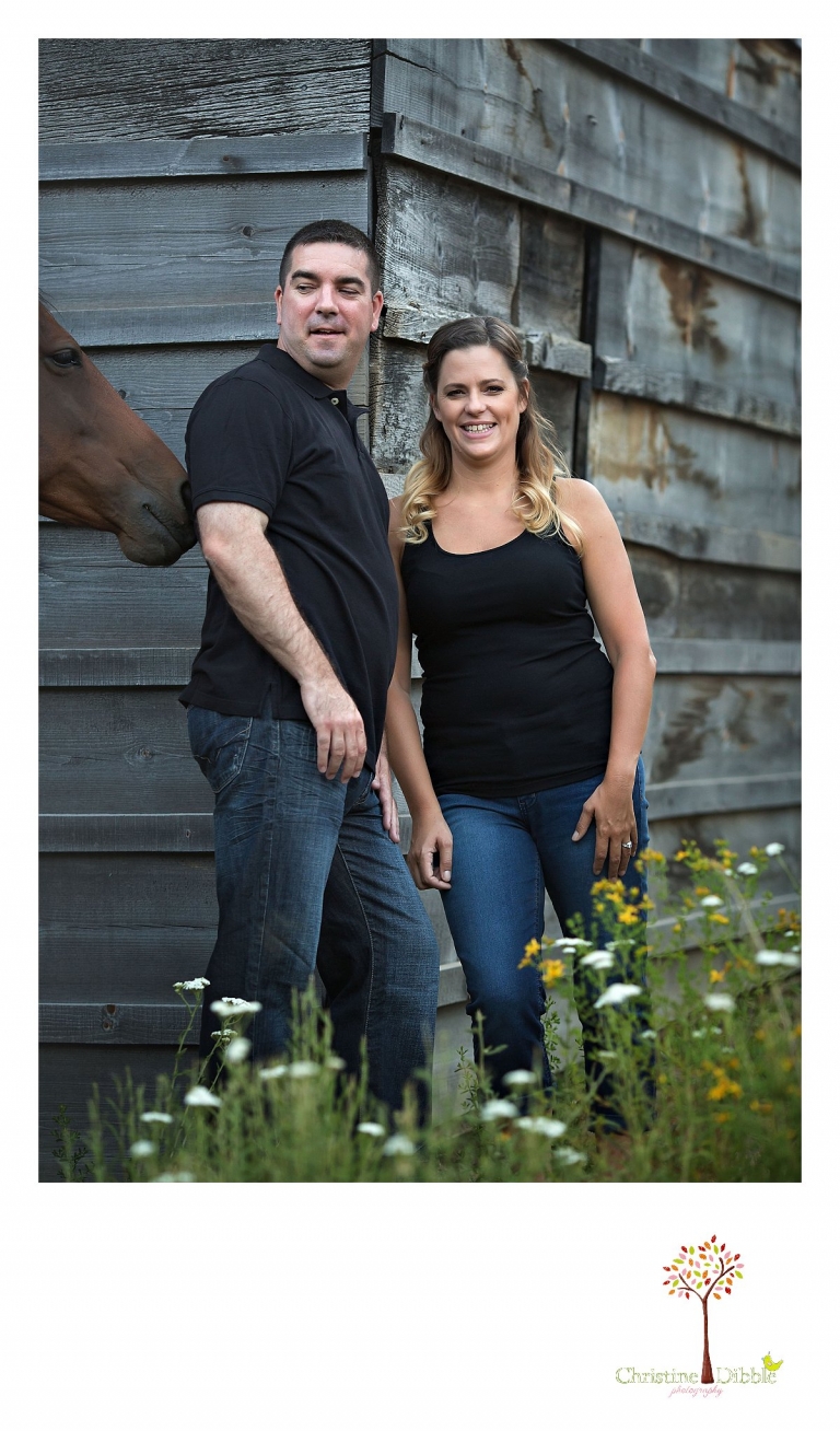An engeged couple laugh as a horse nibbles the groom's shirt while Sonora, CA engagement and wedding photographer Christine Dibble Photography takes their photos.