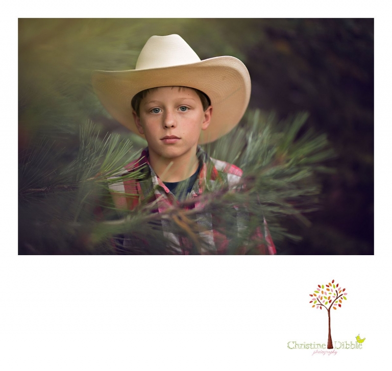 Sonora childrens photographer Christine Dibble Photography takes photos of a young cowboy in his hat among pine trees at Lake Tahoe.