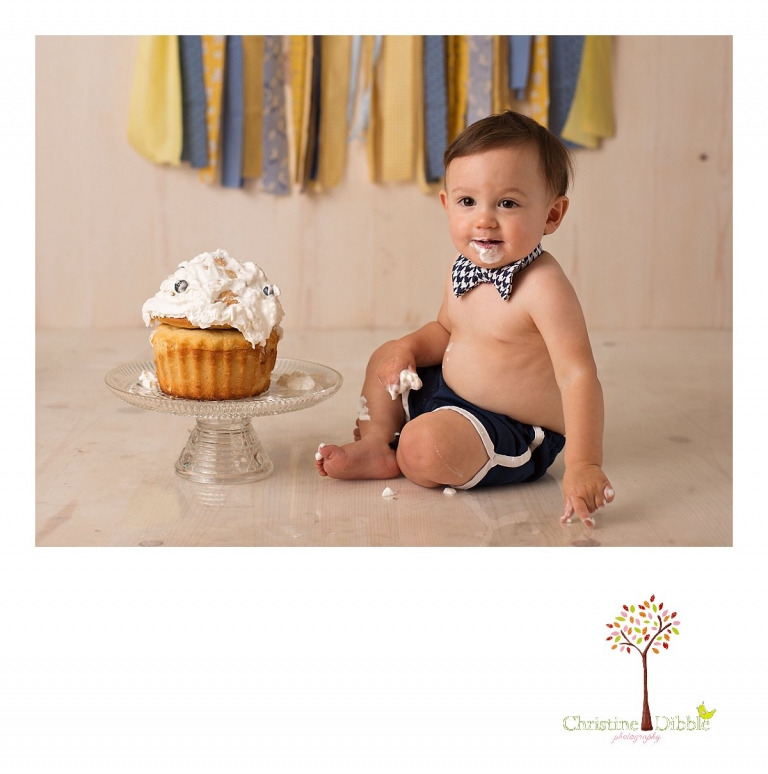 Sonora newborn and baby photographer Christine Dibble Photography takes photos of a baby boy as he smashes a cake for his first birthday with blues and yellows, fruit, and vintage crates and wash tubs.