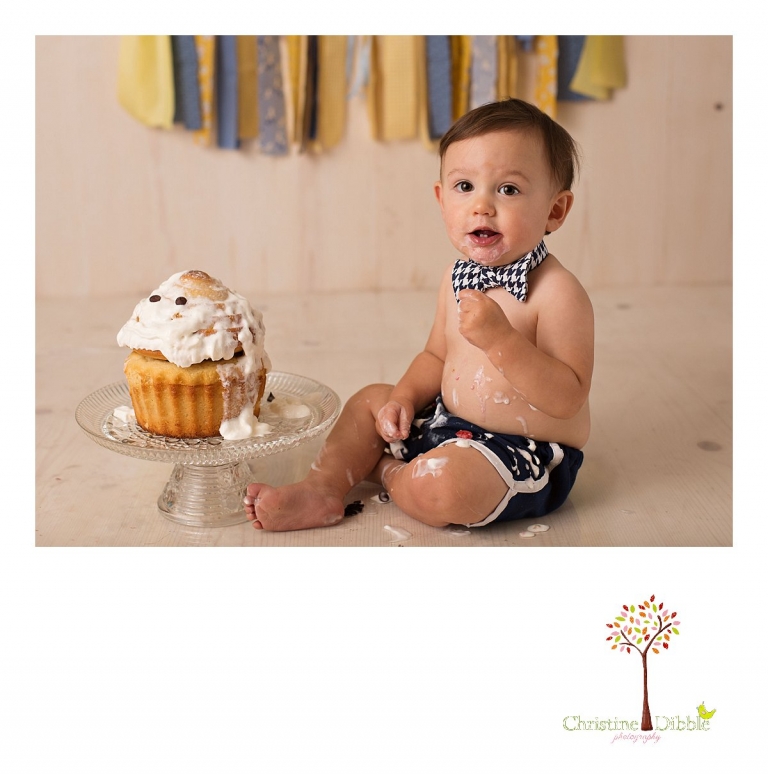 Sonora newborn and baby photographer Christine Dibble Photography takes photos of a baby boy as he smashes a cake for his first birthday with blues and yellows, fruit, and vintage crates and wash tubs.
