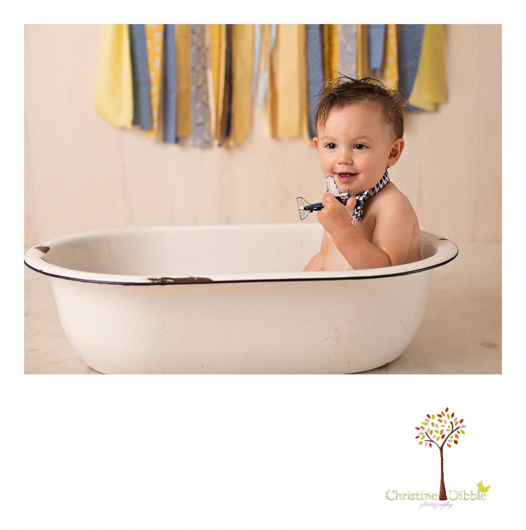 Sonora newborn and baby photographer Christine Dibble Photography takes photos of a baby boy as he smashes a cake for his first birthday with blues and yellows, fruit, and vintage crates and wash tubs.