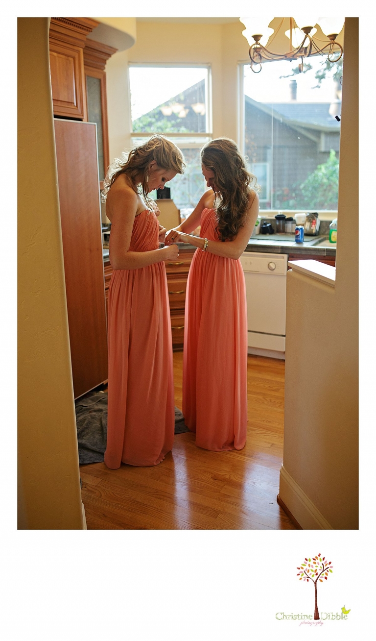 Sonora wedding photographer Christine Dibble Photography  photographs the bridesmaids helping each other dress before  a sunset beach wedding at Moran Lake Beach in Santa Cruz.