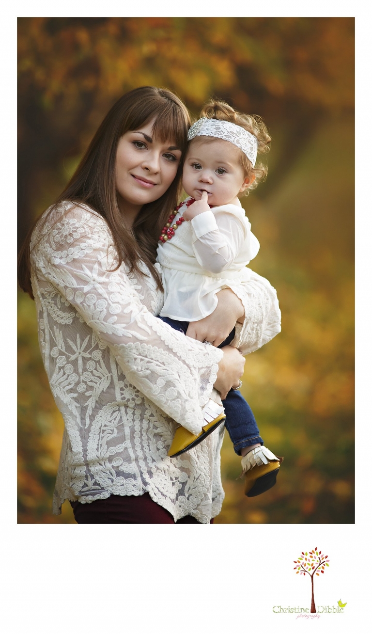 A beautiful mother holds her baby girl during a Sonora family photography session photographed by Christine Dibble Photography at Indigeny Reserve in the fall among the apple orchards.