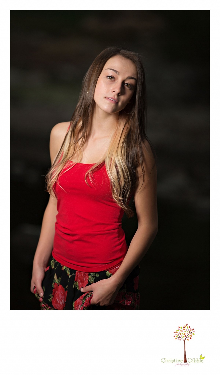 Sonora senior portrait photographer Christine Dibble Photography takes photos outside with lights of a girl in a red tank top and skirt in a dark storm at Jeness Park in the Sierra Nevada Mountains near Cold Springs.