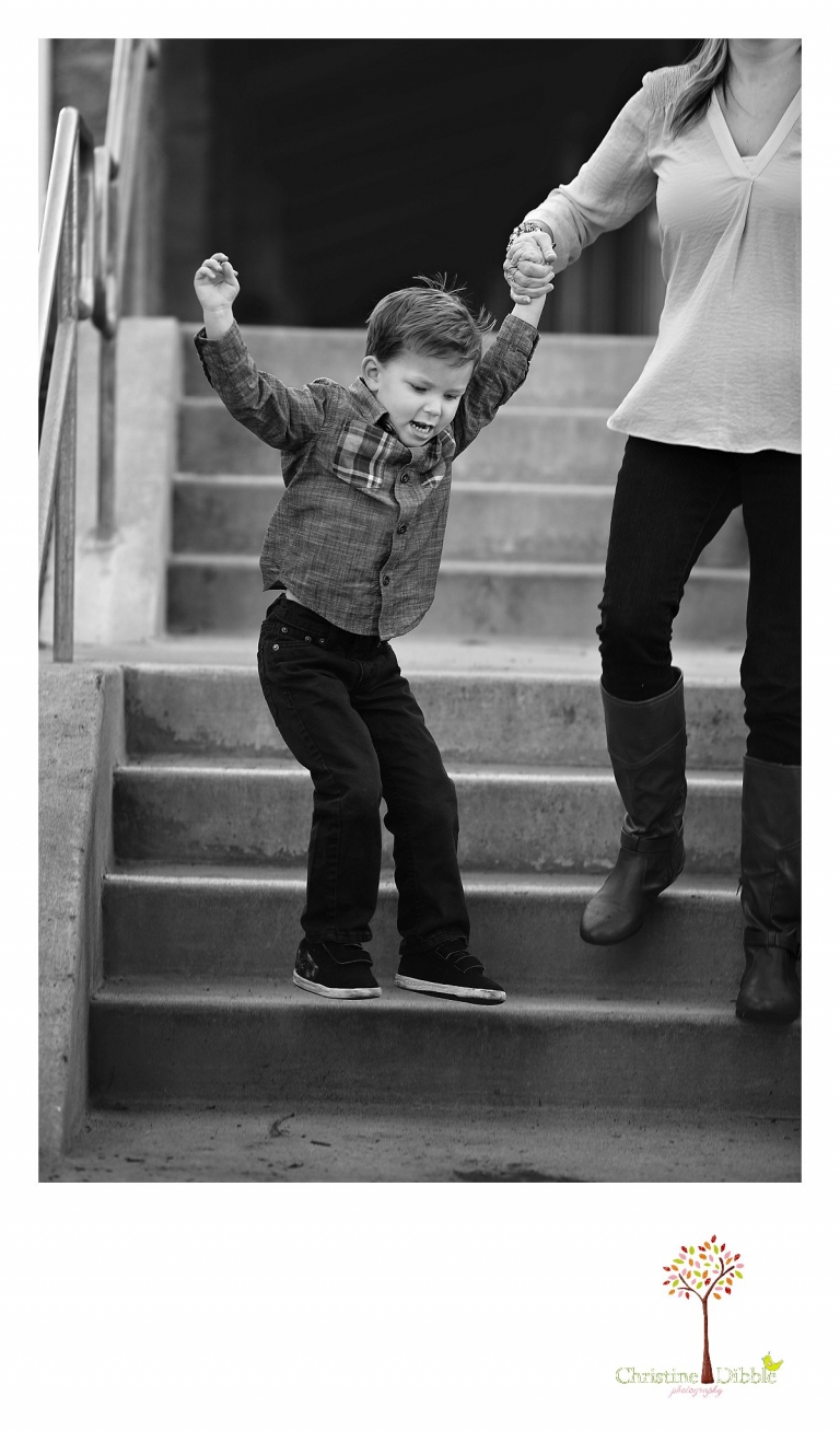 Sonora photography by Christine Dibble Photography captures photos of a little boy holding mom's hand while he jumps off the stairs during mini sessions at Sierra College in Grass Valley.