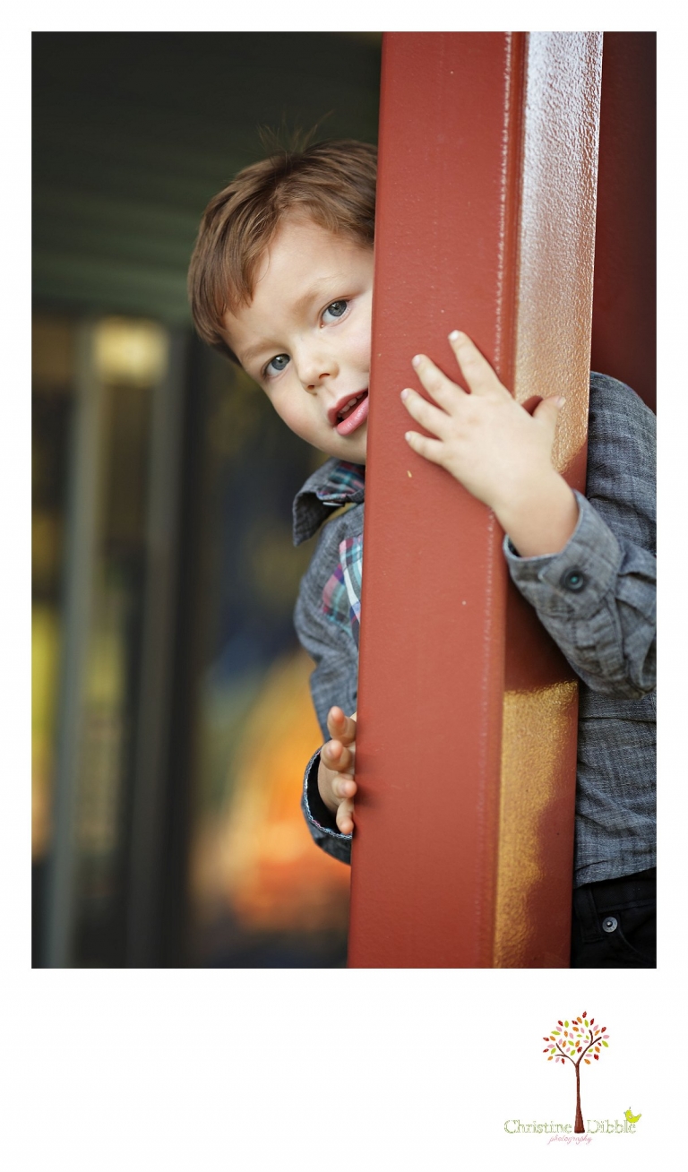 Sonora photography by Christine Dibble Photography captures photos of a little boy peeking around a pillar during mini sessions at Sierra College in Grass Valley.