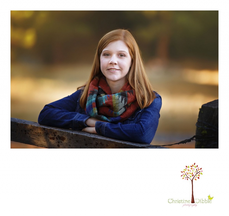 Sonora and Turlock senior portrait photographer Christine Dibble Photography takes outdoor fall senior photos of a girl in a jeans jacket leaning on a rustic ranch fence.
