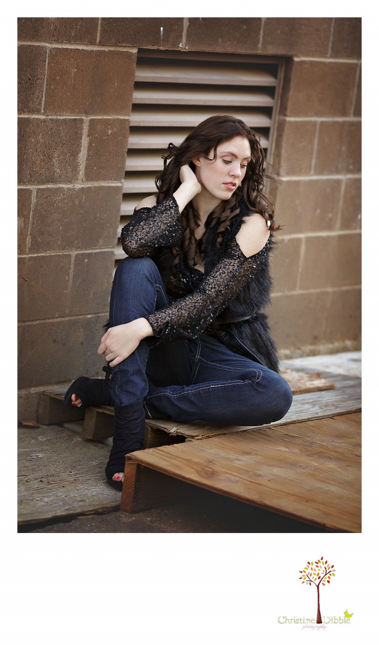 Sonora, CA senior model photographer Christine Dibble takes outdoor modeling photos of a teenage girl for a modeling portfolio while she wears black sequins and a black faux fur vest.