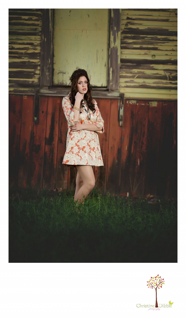 Sonora, CA senior model photographer Christine Dibble takes outdoor modeling photos of a teenage girl for a modeling portfolio while she wears a vintage mod-style coat in front of a weathered building.