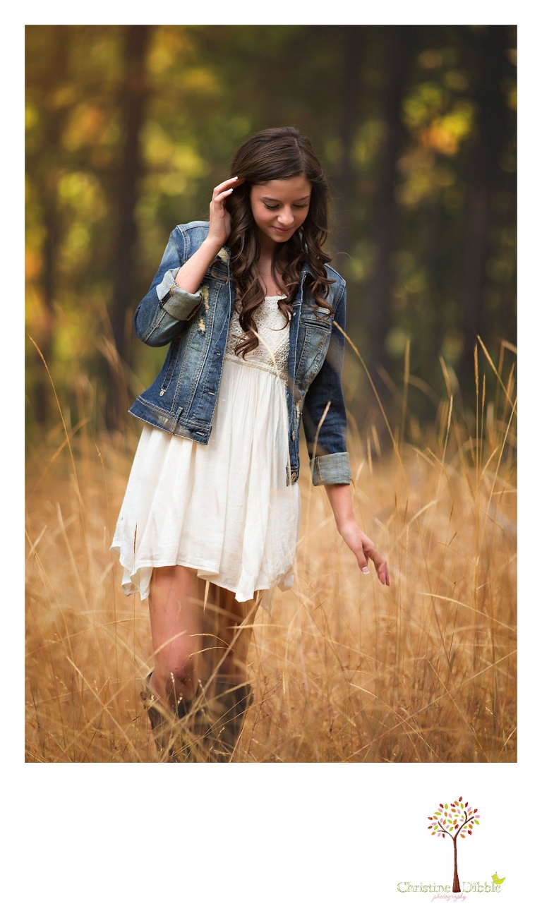 Sonora, Summerville and Turlock senior portrait photographer Christine Dibble Photography takes outdoor senior photos of a girl in a denim jacket, white dress and cowboy boots in a golden Twain Harte field.