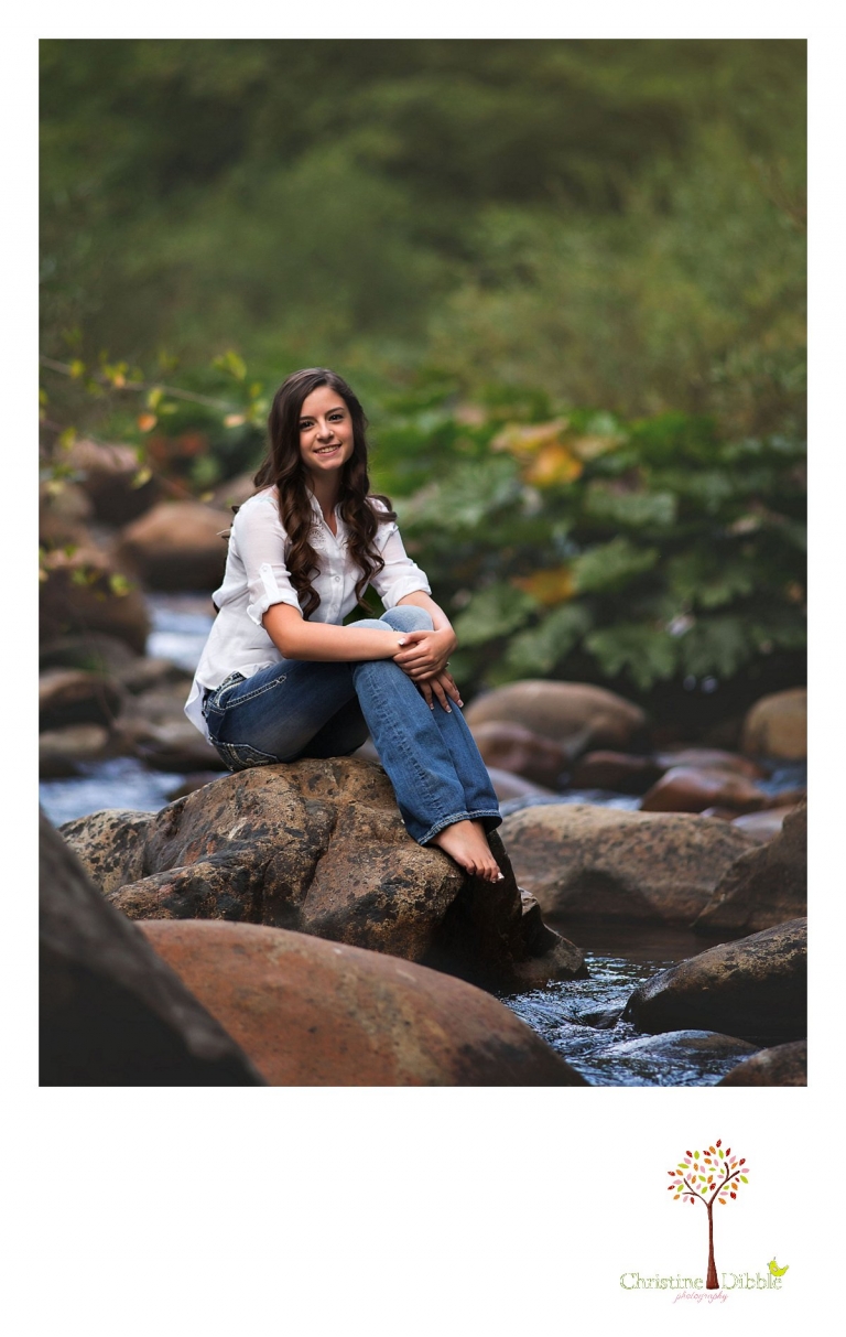 Sonora, Summerville and Turlock senior portrait photographer Christine Dibble Photography takes outdoor senior photos of a girl sitting on a rock in a river.