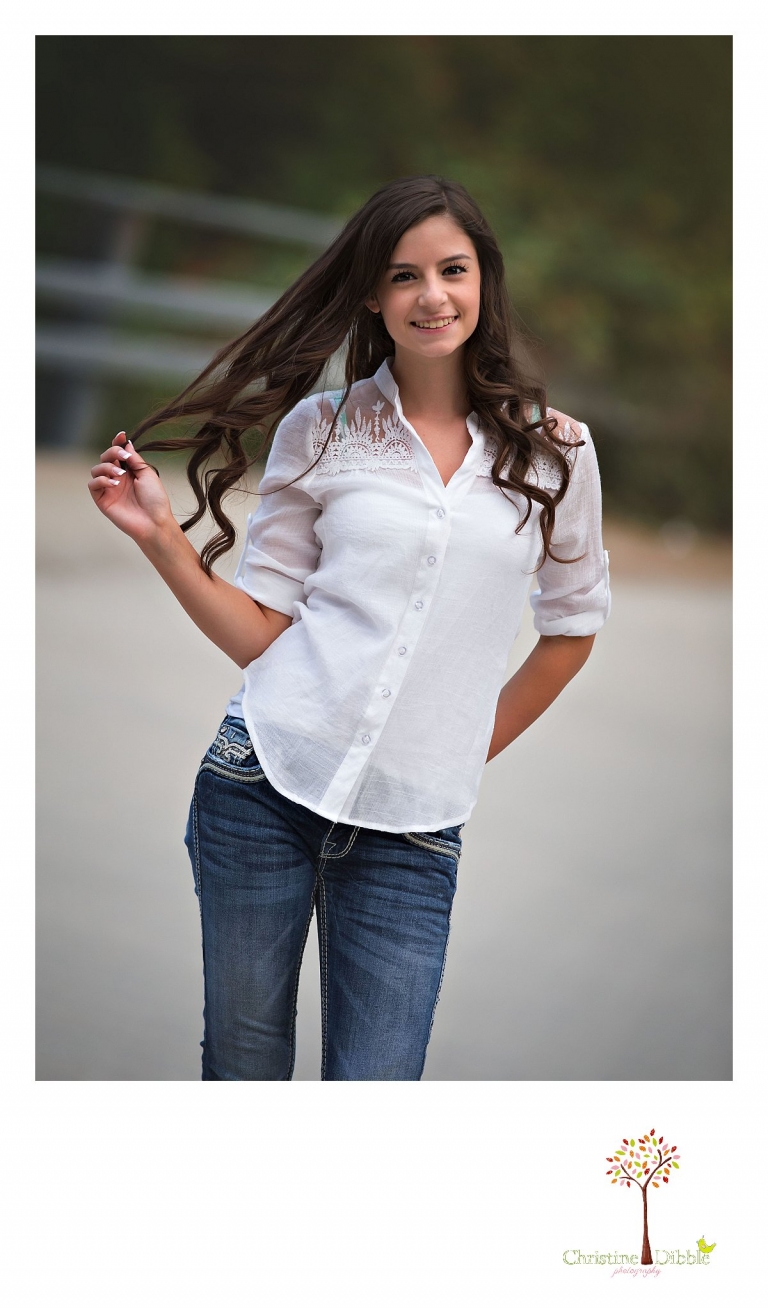 Sonora, Summerville and Turlock senior portrait photographer Christine Dibble Photography takes outdoor senior photos of a girl swinging her long dark haie as she twirls in the road.