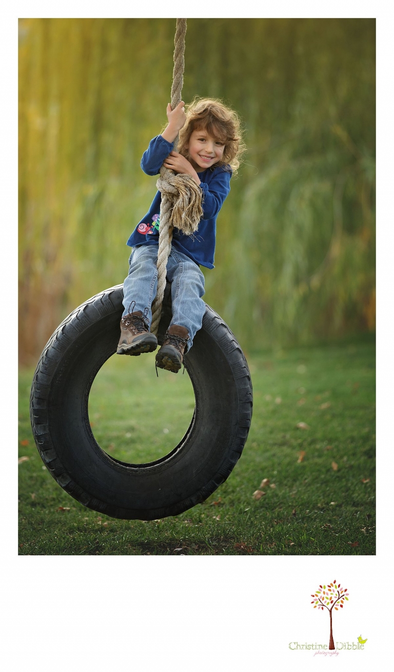 Best Sonora family photographer Christine Dibble Photography takes photos of a little girl on a tire swing during a family photo session outdoors.