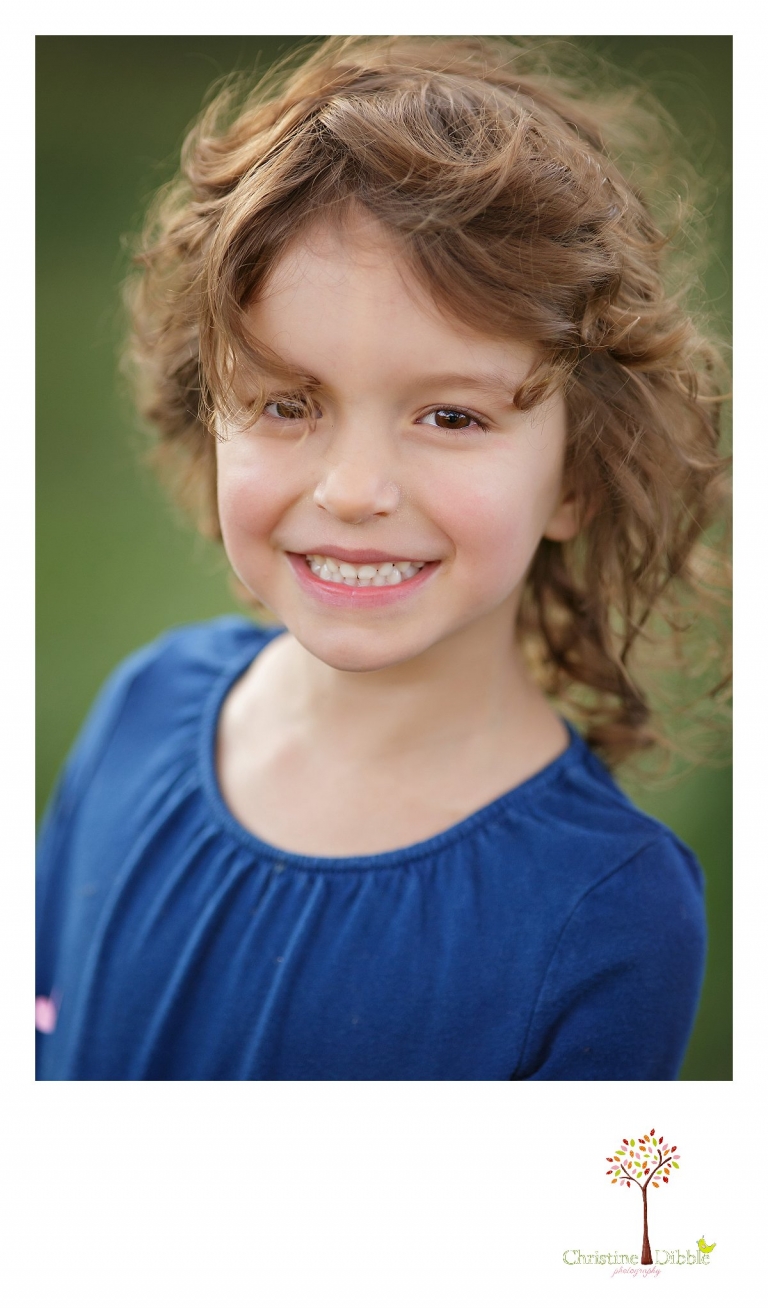 Best Sonora family photographer Christine Dibble Photography takes a head shot of a girl child with curly wind-blown hair.