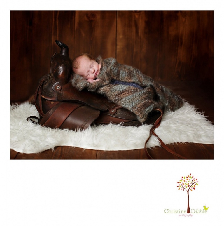 Best Sonora, CA newborn photographer Christine Dibble Photography takes studio photos of a baby boy as he sleeps on a saddle during his newborn photography session.