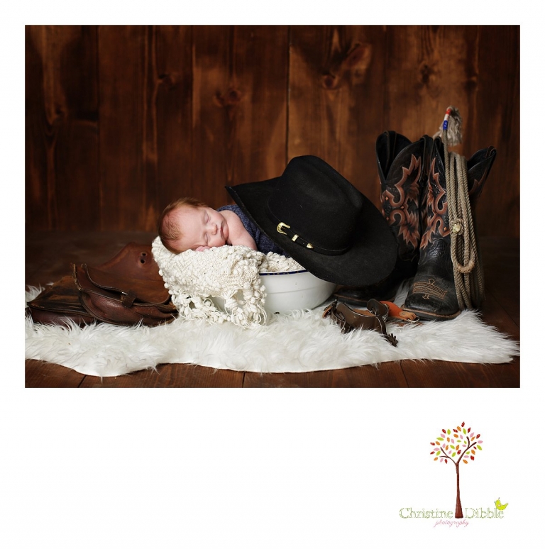 Best Sonora, CA newborn photographer Christine Dibble Photography takes studio photos of a baby boy as he sleeps in an antique wash tub with a saddle and other western gear during his newborn photography session.