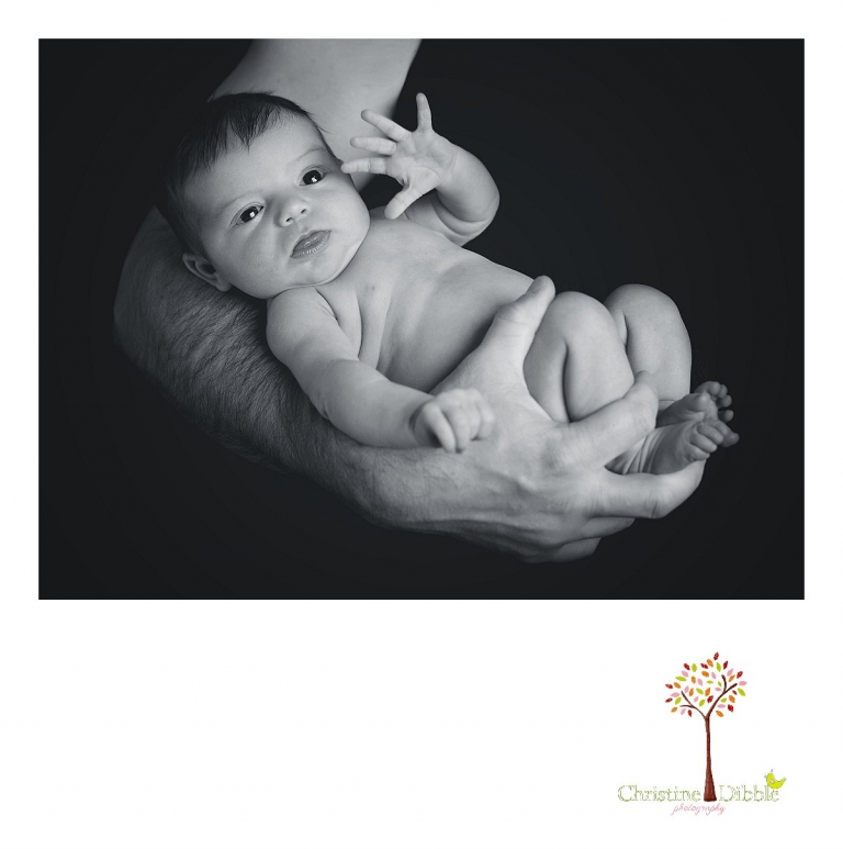 A baby girl, wide awake in daddy's arms, waves for the camera during a Sonora, CA newborn photography session by best Sonora newborn photographer Christine Dibble Photography.