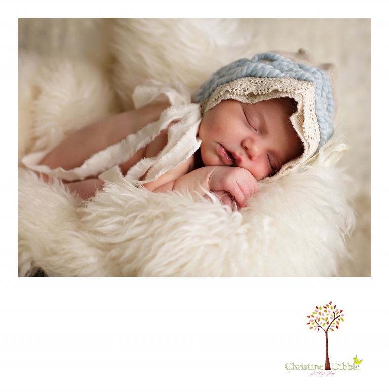 A baby girl sleeps in a bucket and fur while wearing an upcycled bonnet during a Sonora, CA newborn photography session by best Sonora newborn photographer Christine Dibble Photography.