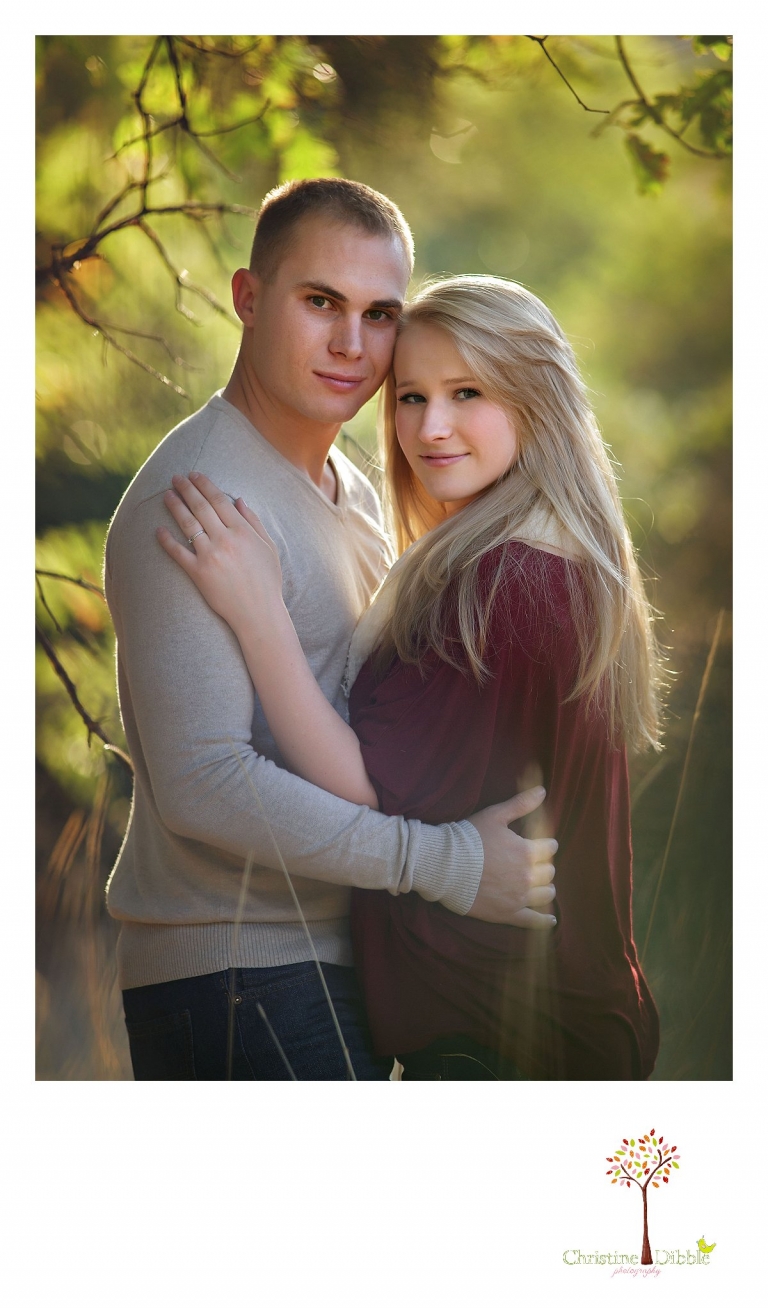 Sonora, CA couple's and engagement photographer Christine Dibble Photography takes romantic engagement style photos of a couple hugging under a tree in a field near Twain Harte at sunset.