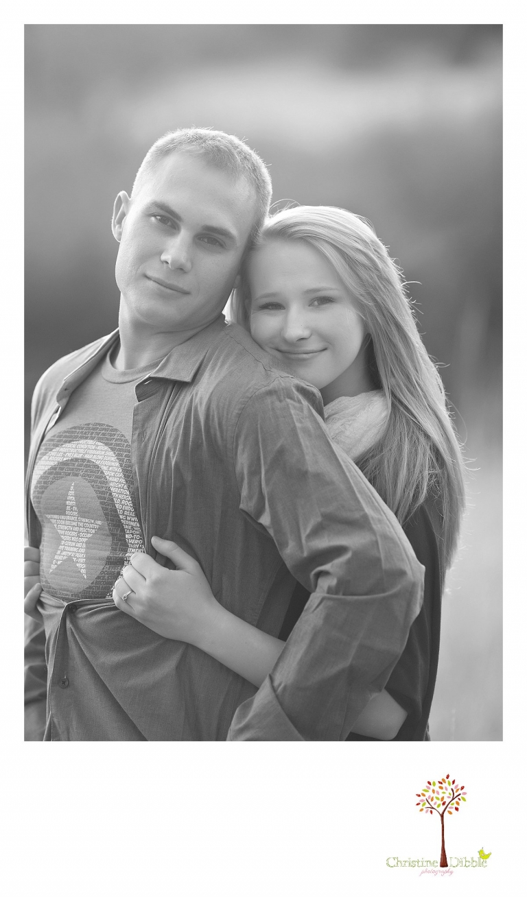 Sonora, CA couple's and engagement photographer Christine Dibble Photography takes romantic black and white engagement style photos of a couple in a field near Twain Harte at sunset as he wears a Captain America shirt.