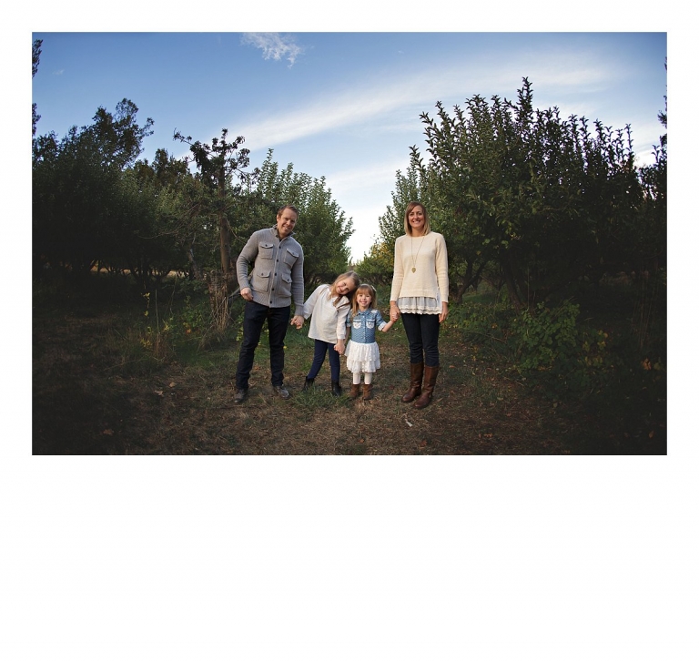 A family poses in front of an orchard row during a Sonora, CA family photography session at Indigeny Reserve by Christine Dibble Photography last autumn.