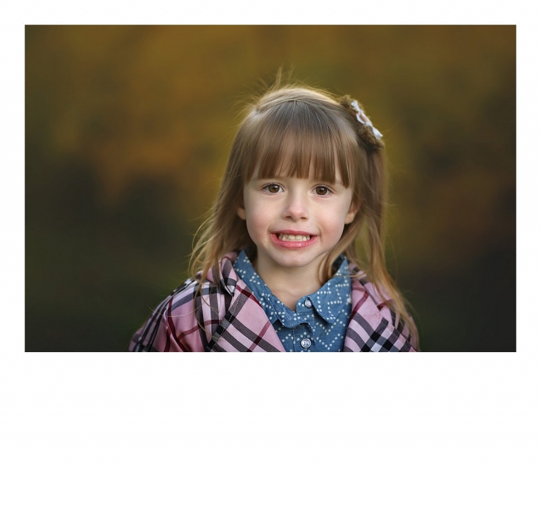 A young girl poses for a child portrait with a fall color background during a Sonora, CA family photography session at Indigeny Reserve by Christine Dibble Photography last fall.
