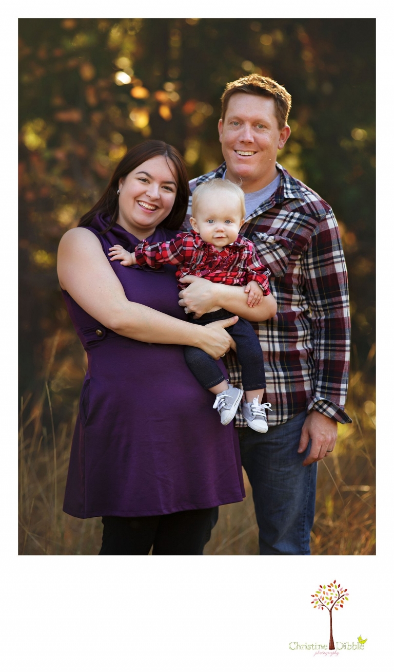 Sonora child photographer Christine Dibble Photography photographs a baby girl's first birthday session outdoors in a field as she poses with mom and dad for a family portrait.