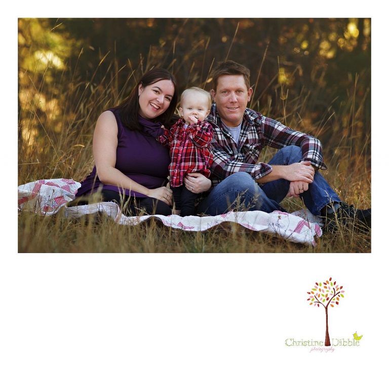 Sonora child photographer Christine Dibble Photography photographs a baby girl's first birthday session outdoors in a field as she sits with mom and dad for a Christmas card portrait.