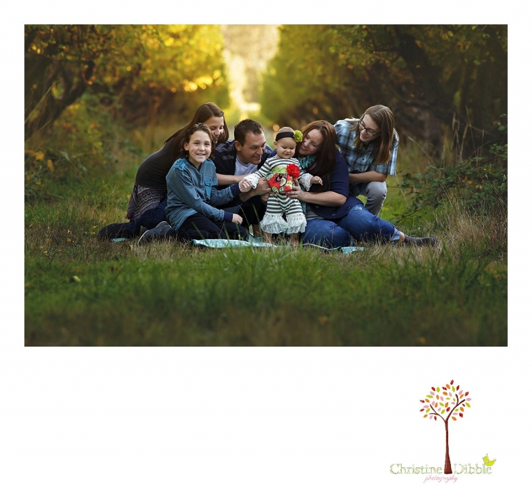 Indigeny Reserve photographer Christine Dibble Photography of Sonora takes family photos of a family with four children among the apple tree rows with fall color behind them.