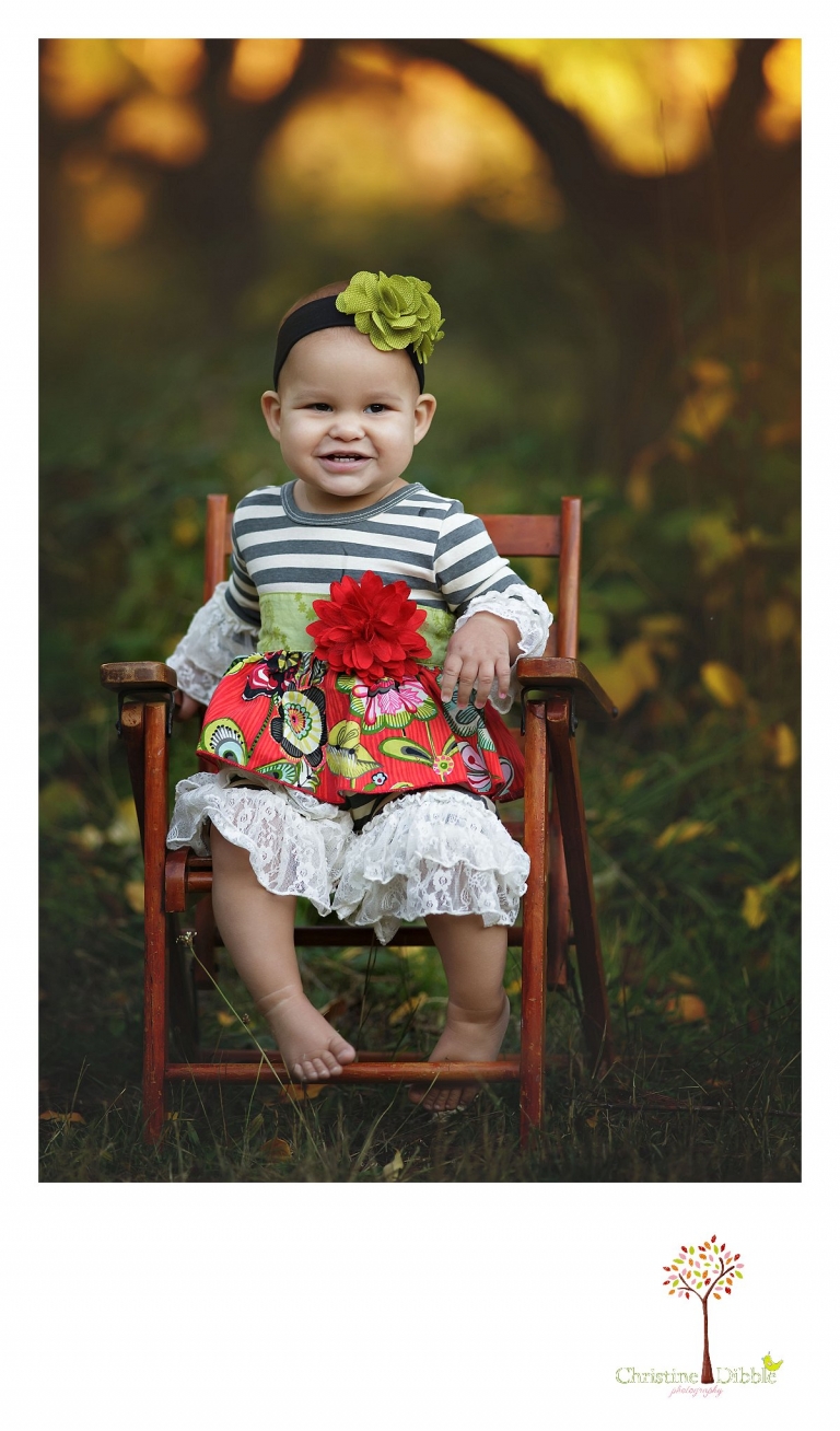 Sonora child and baby photographer Christine Dibble Photography takes first birthday portraits of a baby girl in the apple orchards at Indigeny Reserve as she sits in an antique child's chair.