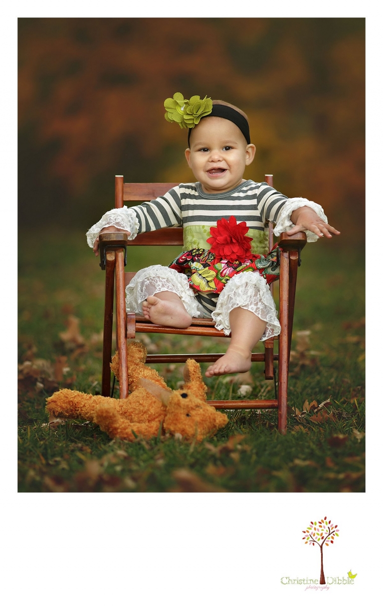Sonora child and baby photographer Christine Dibble Photography takes first birthday portraits of a baby girl in the apple orchards at Indigeny Reserve as she sits in an antique chair and wears bright colored clothes.