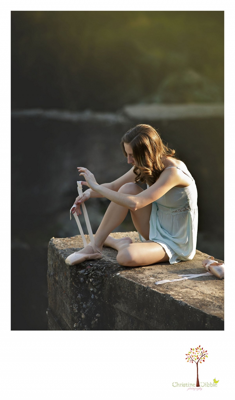 Summerville and Sonora High senior portrait photographer Christine Dibble Photography takes a photo of a girl as she sits on a wall and puts on her toe shoes.