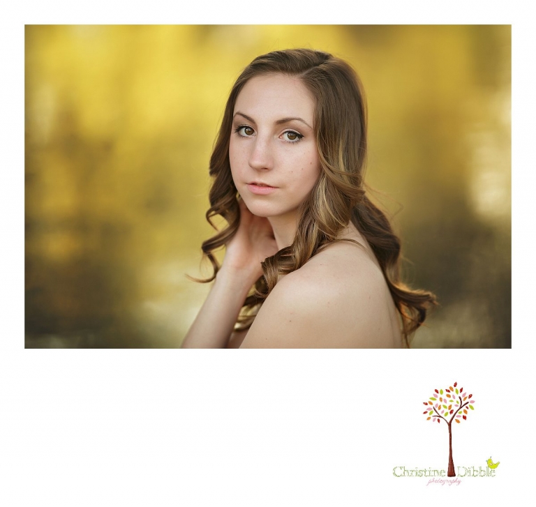 A senior girl poses in front of glowing yellow leaves during her senior portrait session with Summerville and Sonora High senior portrait photographer Christine Dibble Photography.