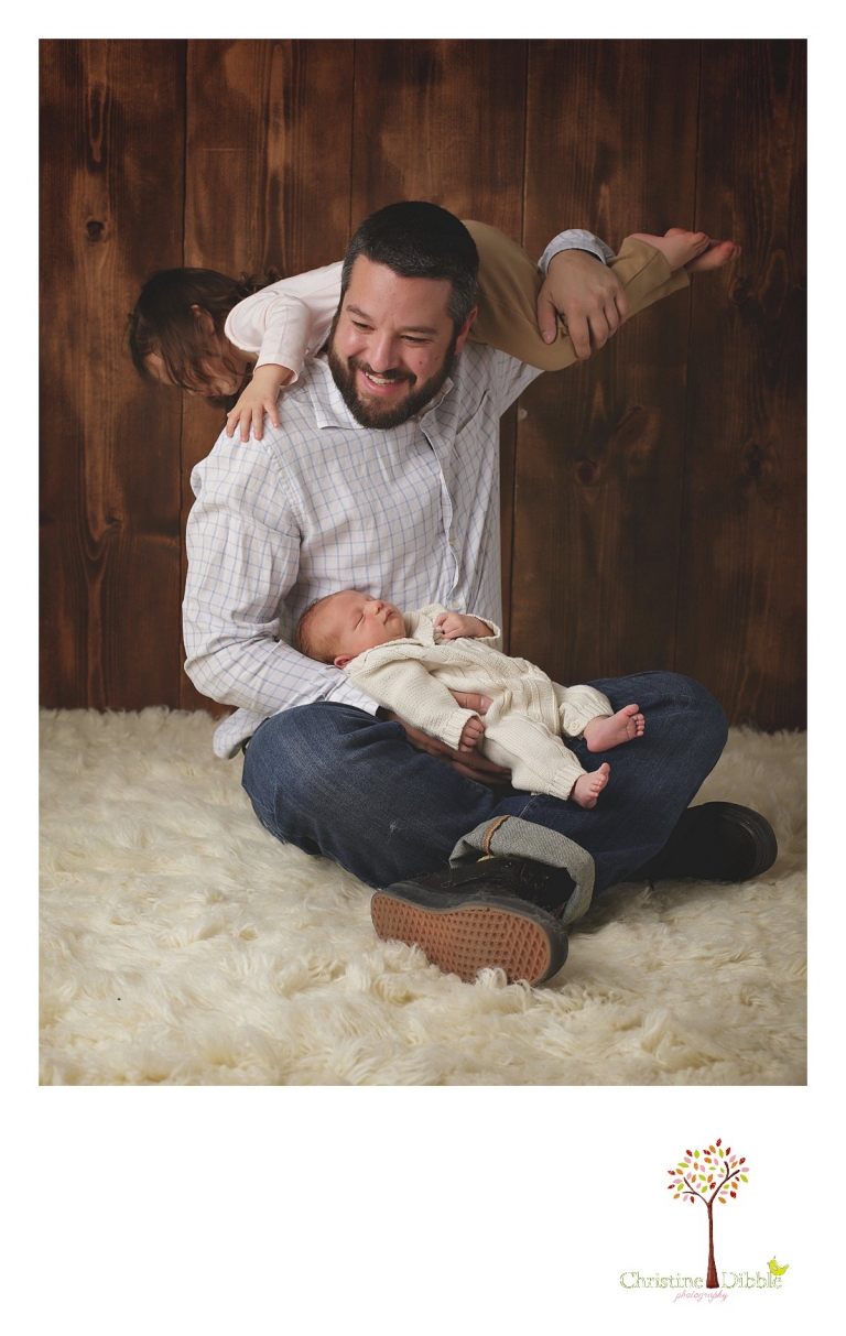 Sonora newborn photographer Christine Dibble Photography takes photos of a baby boy sleeping in Dad's lap as he swings big sister on his shoulders.