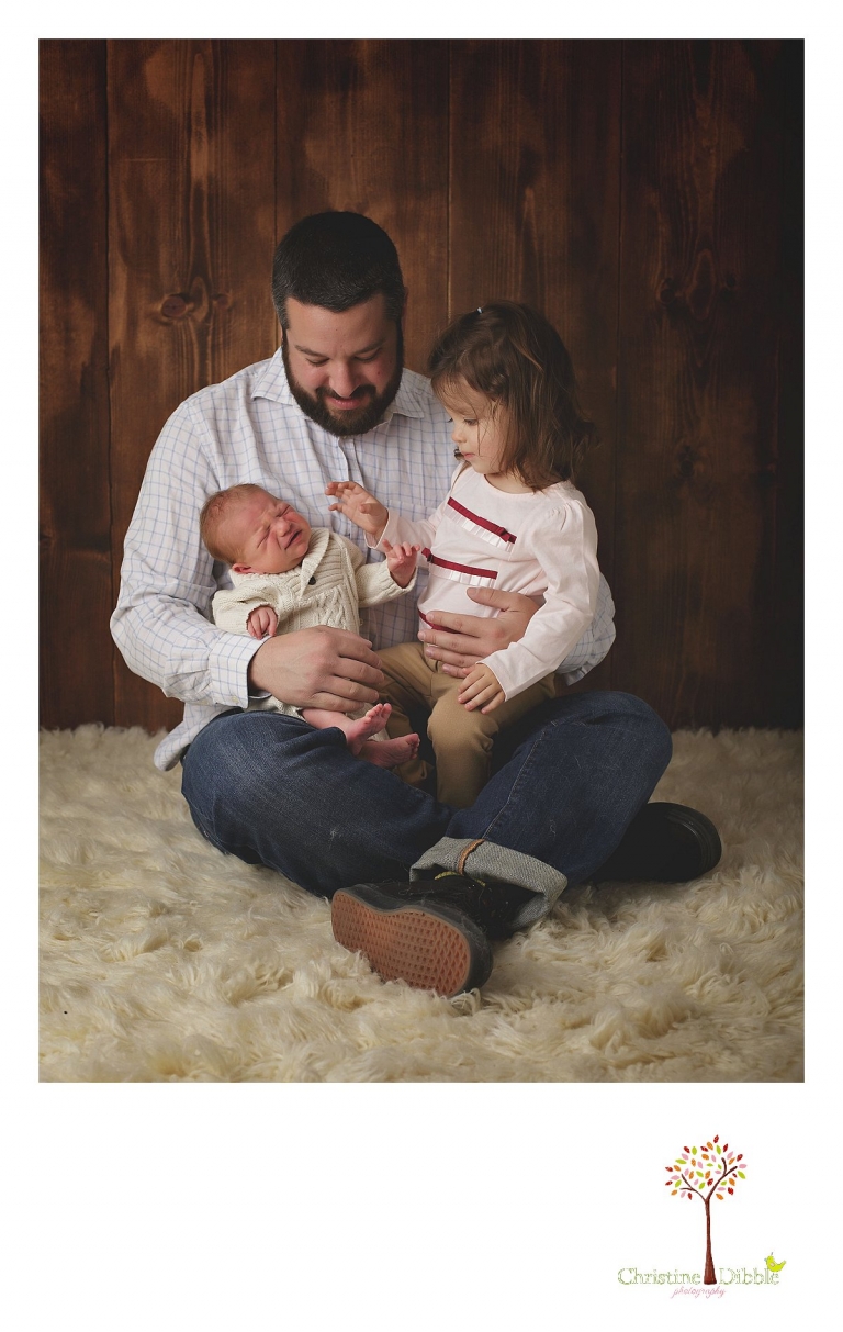 Sonora newborn photographer Christine Dibble Photography takes photos of a big sister as she reaches down to touch her crying baby brother for the first time.