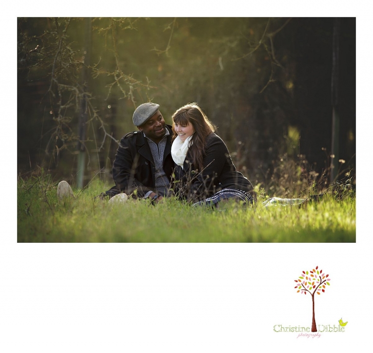 Sonora engagement and wedding photographer Christine Dibble Photography takes photos at Indigeny Reserve of a bride and groom sitting in grass under oak trees with golden sunlight around them.