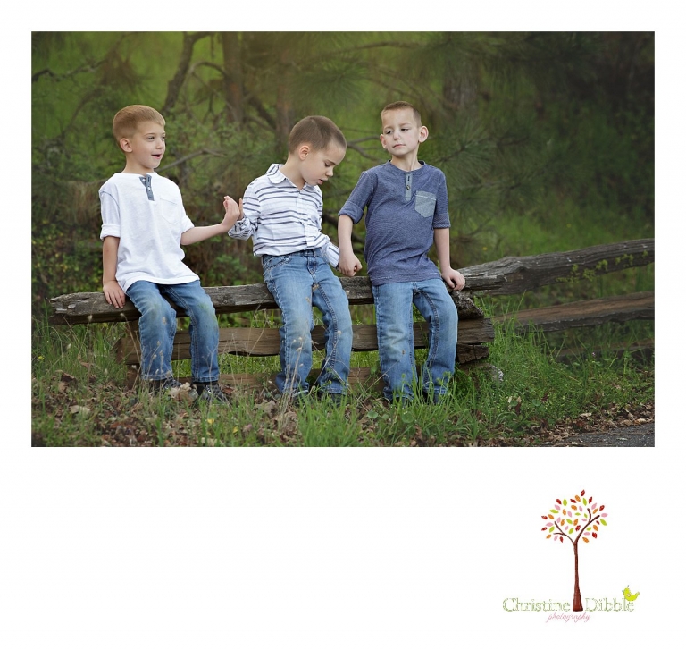Sonora family photographer Christine Dibble Photography takes outdoor family photos at Indigeny Reserve of three cousins sitting on a split rail fence as they say a prayer.