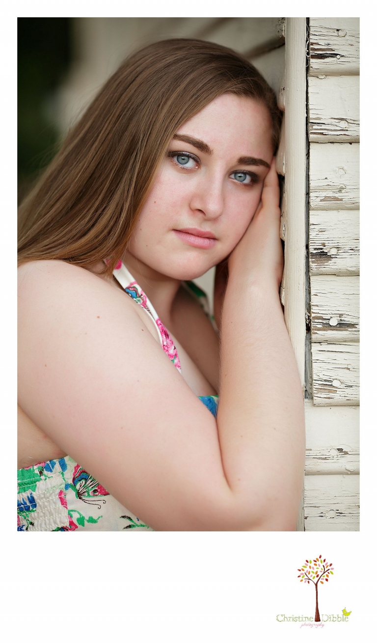 Sonora High senior portrait photographer Christine Dibble Photography takes a photo of a senior girl resting her head against the weathered boards of an old house in Jamestown.