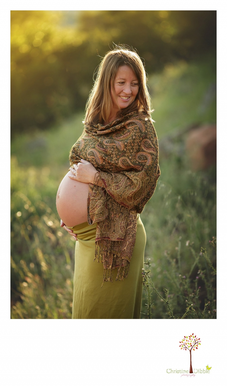 Sonora maternity photographer Christine Dibble Photography takes outdoor sunset photos of a pregnant woman showing off her baby belly bump in a skirt and shawl.