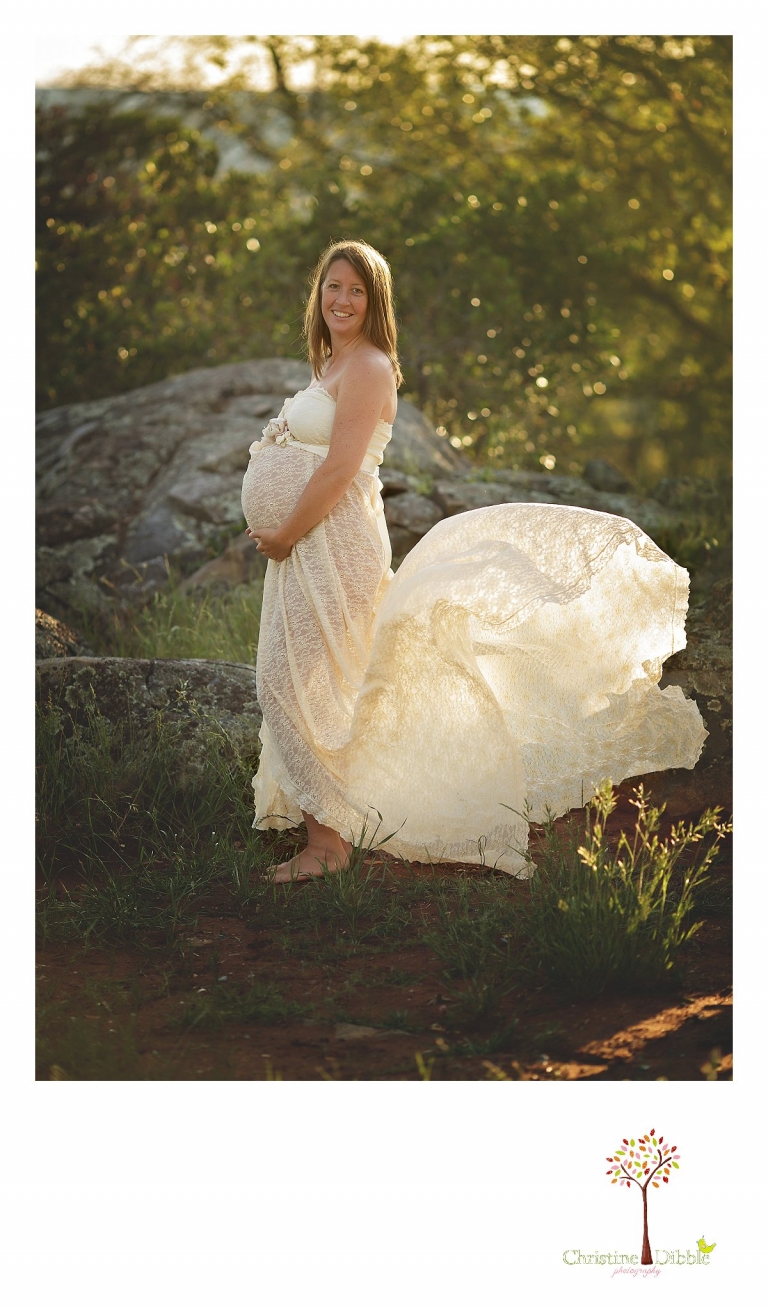 The lace of a maternity dress billows behind a pregnant woman photographed by Sonora maternity photographer Christine Dibble Photography during an outdoor sunset shoot.