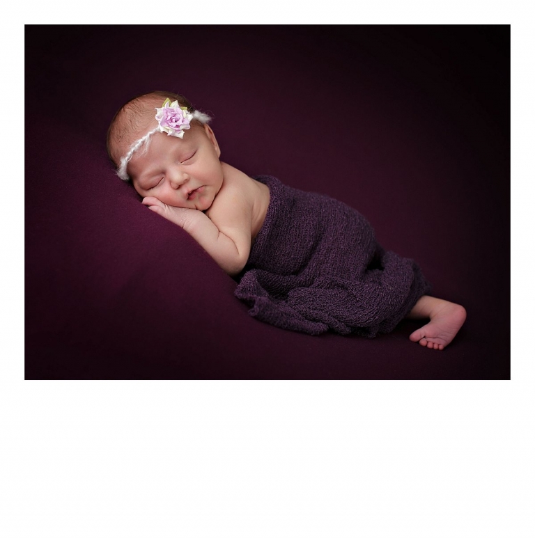 Sonora newborn photographer Christine Dibble Photography takes newborn portraits of a baby girl on a blanket while wrapped in a wrap and a headband with a flower.