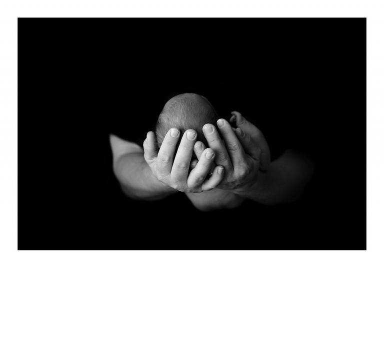 Sonora newborn photographer Christine Dibble Photography takes portraits of dad's hands holding a newborn baby's head in black and white.