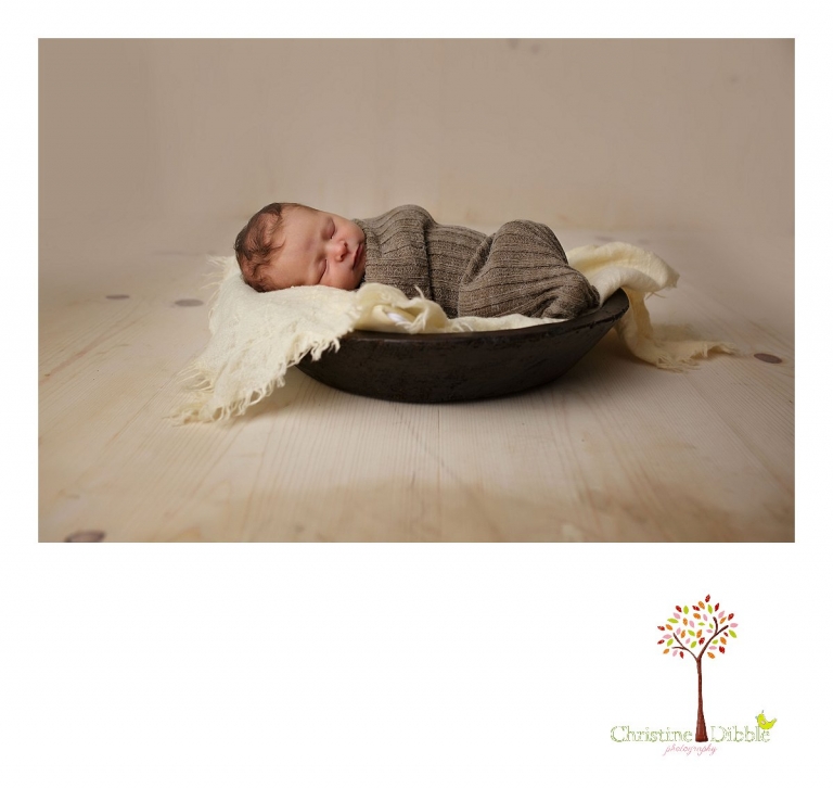Best Sonora newborn photographer Christine Dibble Photography takes indoor studio photos of a newborn baby girl as she sleeps in a wooden bowl.
