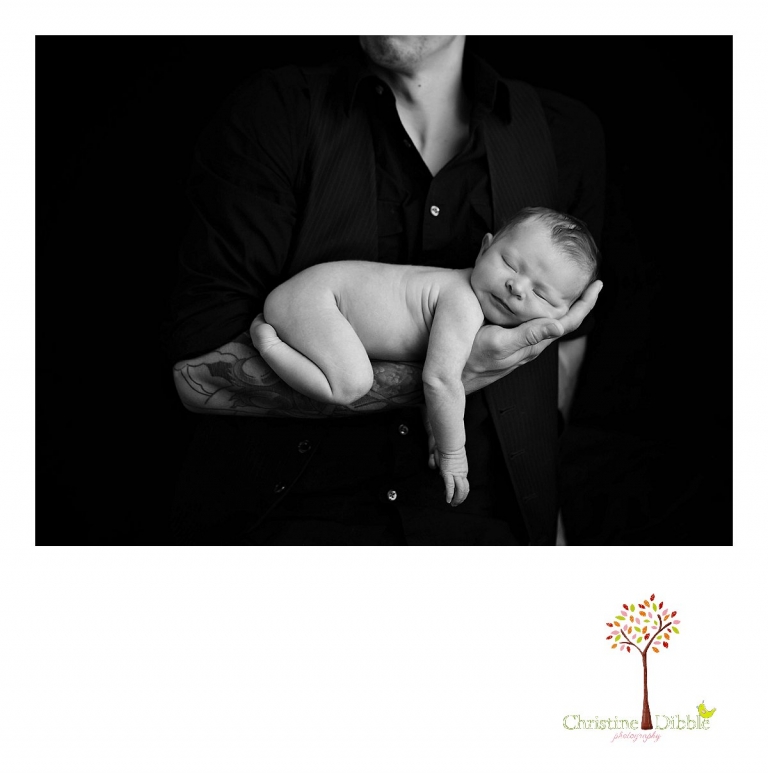 Best Sonora newborn photographer Christine Dibble Photography takes indoor studio photos of a newborn baby girl sleeping on dad's tattooed arms.