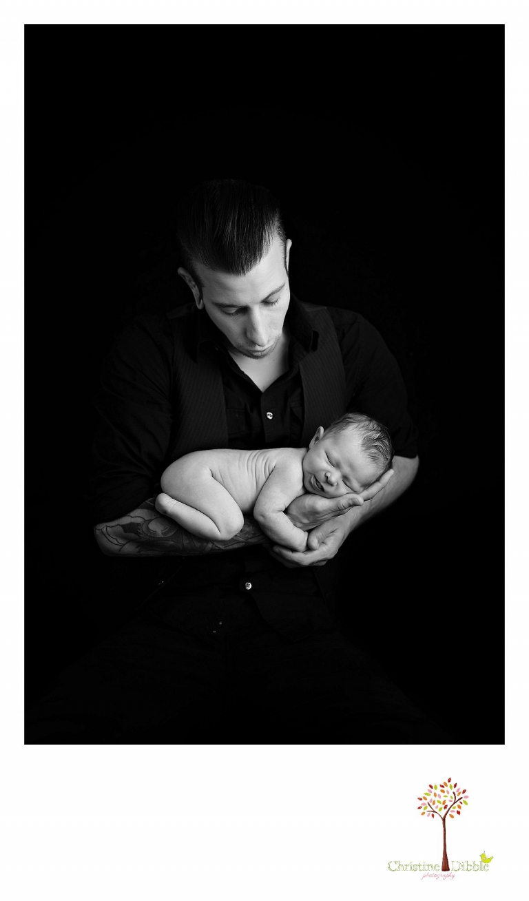 Best Sonora newborn photographer Christine Dibble Photography takes indoor studio photos of a newborn baby girl sleeping in dad's arms as he looks down at her.
