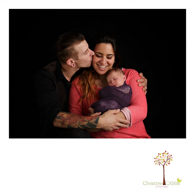 Best Sonora newborn photographer Christine Dibble Photography takes indoor studio photos of a newborn baby girl and her first family photo as dad kisses mom on the cheek.